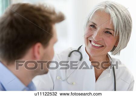 Stock Image - Doctor talking to man in office. Fotosearch