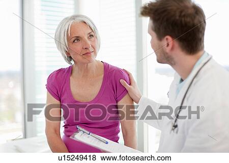 Doctor talking to woman in office View Large Photo Image Stock Photo - Doctor talking to woman in office. Fotosearch