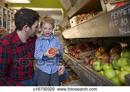 Stock Photo - Father and son buying produce in store. Fotosearch