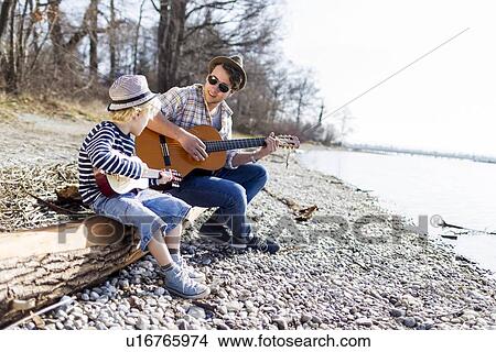 Father and son playing guitars by creek View Large Photo Image Picture - Father and son playing guitars by creek. Fotosearch