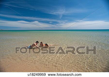 Stock Photo - Friends playing in surf on beach. Fotosearch