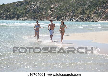 Friends running in waves on beach View Large Photo Image Stock Image - Friends running in waves on beach. Fotosearch