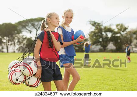 Stock Photo - Girl carrying soccer balls on pitch. Fotosearch