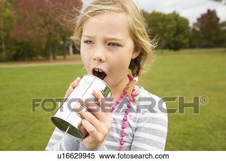Stock Photography - Girl playing with tin can telephone. Fotosearch
