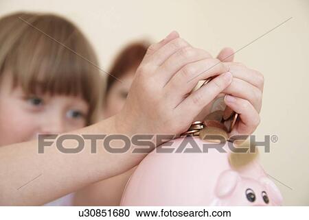 Girl putting money in piggy bank View Large Photo Image Stock Image - Girl putting money in piggy bank. Fotosearch