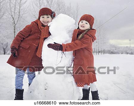 Girls building snowman outdoors View Large Photo Image Stock Image - Girls building snowman outdoors. Fotosearch