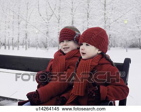Stock Photography - Girls sitting on bench in snow. Fotosearch