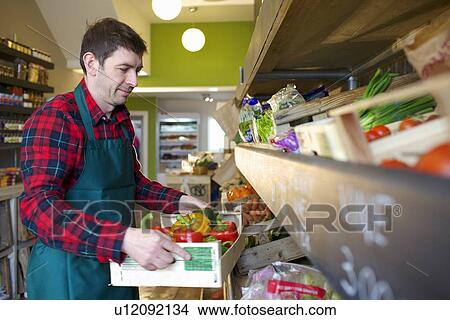 Picture - Grocer arranging produce for sale. Fotosearch