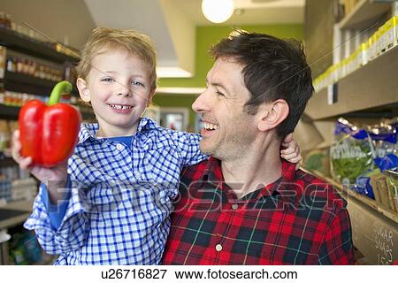 Grocer holding son with bell pepper View Large Photo Image Stock Photo - Grocer holding son with bell pepper. Fotosearch