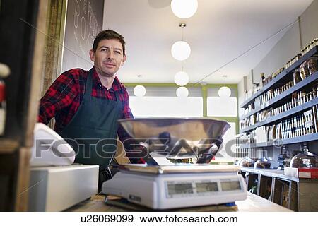 Stock Photo - Grocer working behind counter at store. Fotosearch