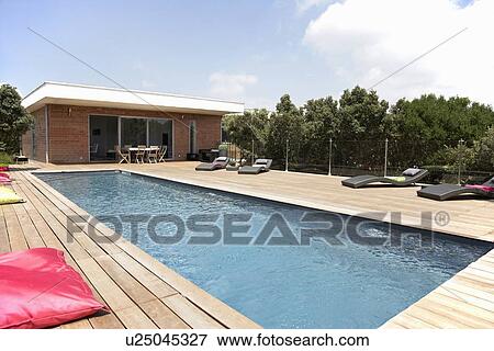 Stock Photo - Lawn chairs and pool on modern deck. Fotosearch