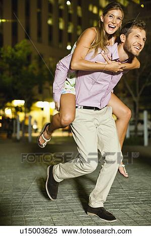 Stock Photography - Man carrying girlfriend on city street. Fotosearch