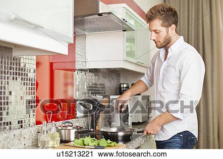 Stock Image - Man cooking in kitchen. Fotosearch