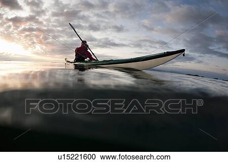 Stock Image - Man kayaking on still lake. Fotosearch