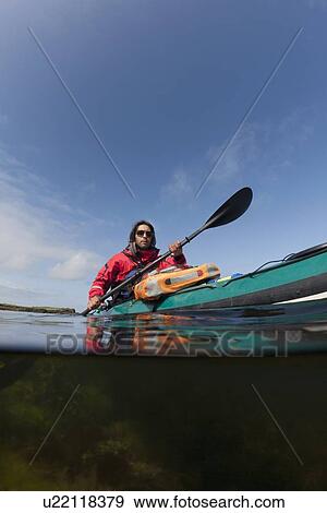 Stock Photo - Man kayaking on still lake. Fotosearch