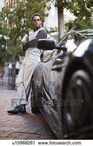 Stock Image - Man leaning on sports car. Fotosearch