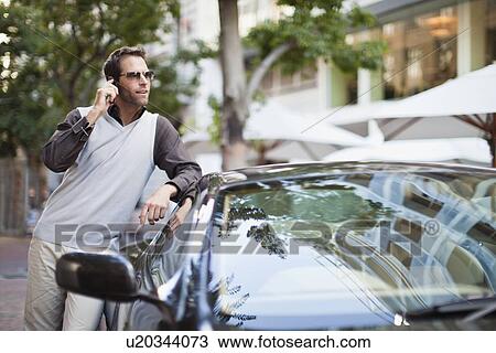 Stock Image - Man leaning on sports car. Fotosearch