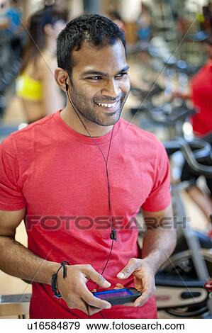 Man listening to headphones in gym View Large Photo Image Stock Photo - Man listening to headphones in gym. Fotosearch