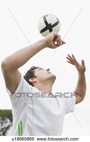 Stock Photo - Man playing with soccer ball in field. Fotosearch