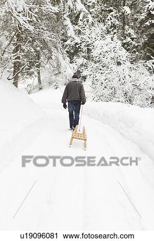 Man pulling sled in snowy field View Large Photo Image Stock Image - Man pulling sled in snowy field. Fotosearch