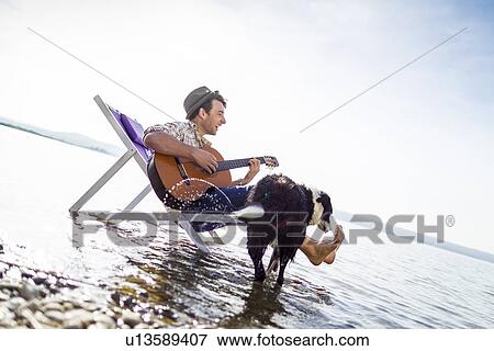 Stock Photo - Man with dog in lawn chair in creek. Fotosearch