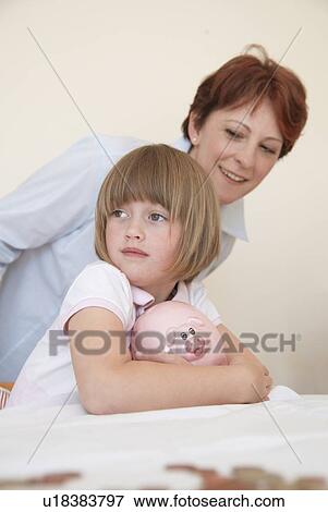 Stock Photo - Mother and daughter with piggy bank. Fotosearch