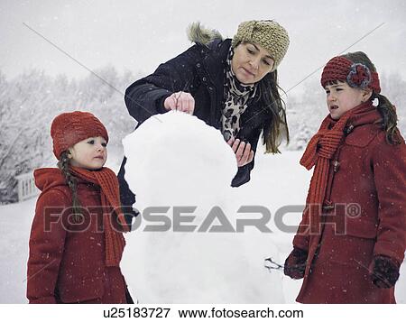 Mother and daughters building snowman View Large Photo Image Stock Photo - Mother and daughters building snowman. Fotosearch