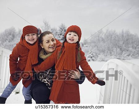 Stock Photograph - Mother and daughters playing in snow. Fotosearch
