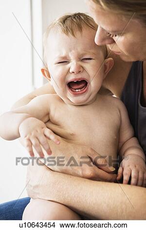 Mother holding crying baby girl View Large Photo Image Picture - Mother holding crying baby girl. Fotosearch