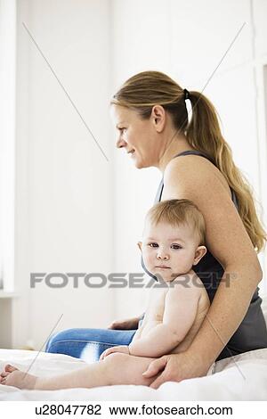 Mother sitting with baby girl on bed View Large Photo Image Stock Image - Mother sitting with baby girl on bed. Fotosearch