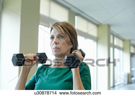 Older woman lifting weights in gym View Large Photo Image Picture - Older woman lifting weights in gym. Fotosearch