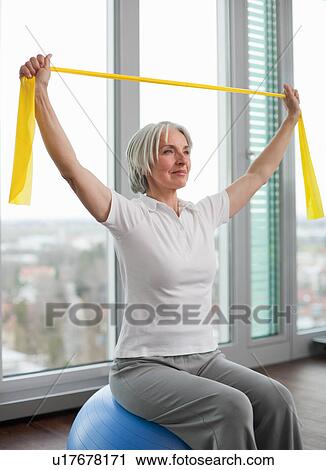 Stock Image - Older woman stretching in gym. Fotosearch