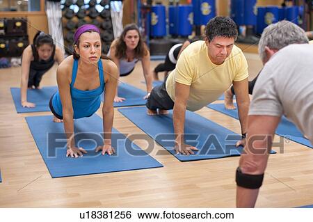 Stock Photograph - People practicing yoga in studio. Fotosearch