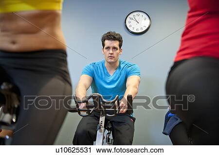 Stock Image - People using spin machines in gym. Fotosearch