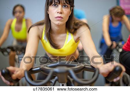 Stock Image - People using spin machines in gym. Fotosearch