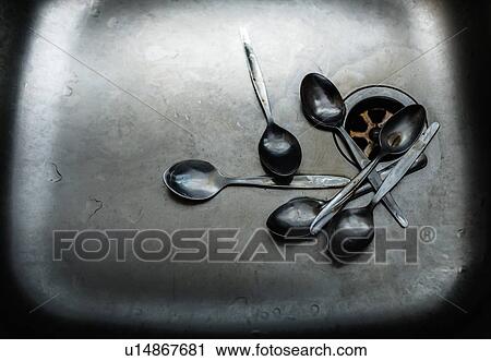 Stock Image - Pile of dirty spoons in sink. Fotosearch
