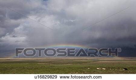 Stock Photo - Rainbow stretching over rural landscape. Fotosearch