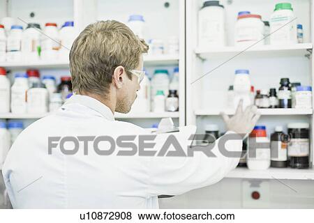 Stock Photo - Scientist examining jars in lab. Fotosearch
