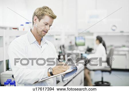 Picture - Scientist writing on clipboard in lab. Fotosearch
