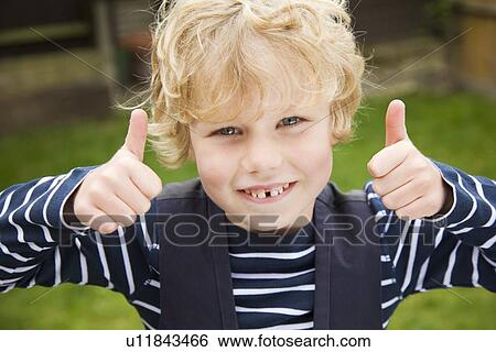 Stock Photograph - Smiling boy giving thumbs-up outdoors. Fotosearch