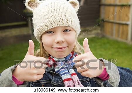 Stock Photo - Smiling girl giving thumbs-up outdoors. Fotosearch