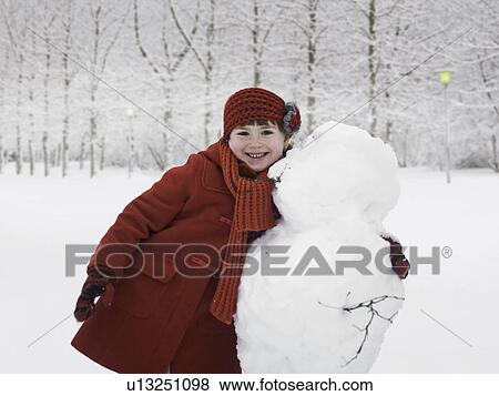 Smiling girl hugging snowman outdoors View Large Photo Image Stock Photo - Smiling girl hugging snowman outdoors. Fotosearch