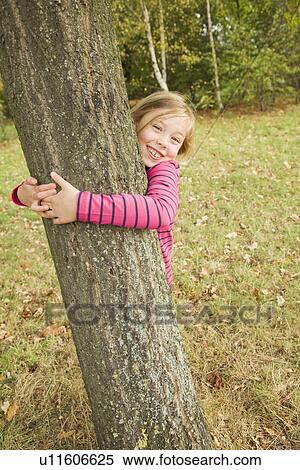 Smiling girl hugging tree outdoors View Large Photo Image Stock Photography - Smiling girl hugging tree outdoors. Fotosearch
