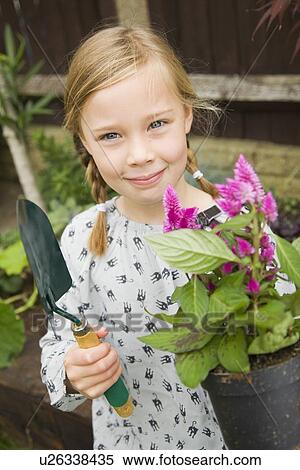 Smiling girl planting flowers outdoors View Large Photo Image Stock Photography - Smiling girl planting flowers outdoors. Fotosearch