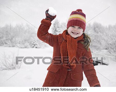 Stock Image - Smiling girl throwing snowball. Fotosearch