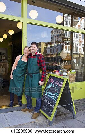 Smiling grocers standing outside store View Large Photo Image Stock Image - Smiling grocers standing outside store. Fotosearch