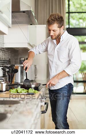 Smiling man cooking in kitchen View Large Photo Image Stock Image - Smiling man cooking in kitchen. Fotosearch