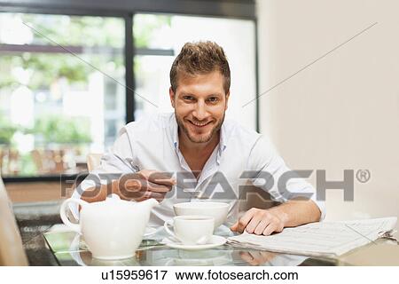Stock Photo - Smiling man eating breakfast at table. Fotosearch