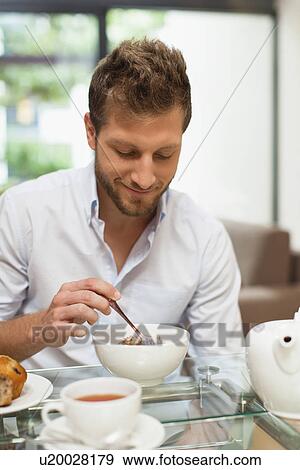 Smiling man eating breakfast at table View Large Photo Image Stock Photo - Smiling man eating breakfast at table. Fotosearch