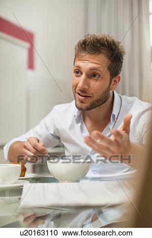 Stock Image - Smiling man talking at breakfast. Fotosearch